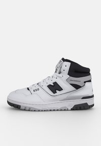 White and black New Balance 650 high-top sneaker with laces, perforated side panels, and rubber sole on a plain background.