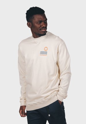 Cremefarbener Sweatshirt mit geripptem Ausschnitt, ausgestattet mit einem kleinen Logo und einer Wellen-Grafik in Blau und Orange. Weicher, lässiger Stoff.