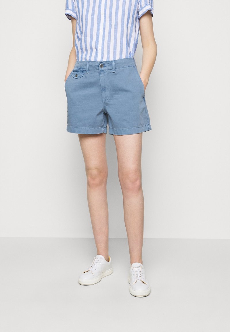 Ljust blå bomullsshorts med en mjuk struktur, sidofickor och knappstängning. Kombineras med en randig kortärmad skjorta och vita sneakers.