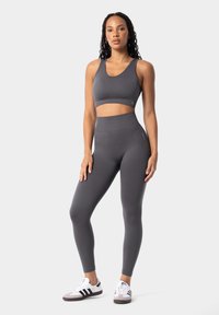 Top corto atlético gris y leggings de cintura alta hechos de material elástico, combinados con zapatillas negras y blancas.