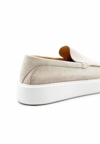 Beige suède instapschoen met een ronde neus en een dikke witte zool. Heeft een zachte textuur en minimale stiksels langs de randen.