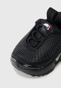 Μαύρο αθλητικό παπούτσι με υφασμάτινη επένδυση με υφή, στρογγυλή μ�ύτη, ελαστικά κορδόνια, θηλιά πίσω και μαλακή σόλα με μικρή ορατή μονάδα αέρα.