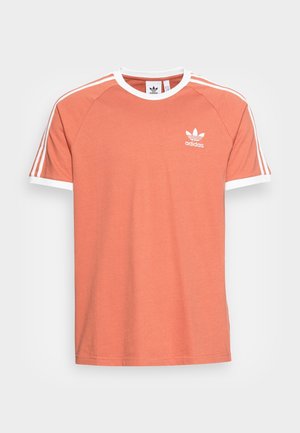 Kortærmet koralfarvet Adidas T-shirt med hvid rund hals, hvide ærmekanter, tre hvide striber på skuldrene og Adidas-logo på brystet.