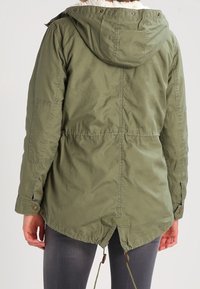 Olivgrüne Parka-Jacke mit Kapuze, strukturiertem Stoff, Kordelzug in der Taille und Druckknopfverschluss an den Manschetten, mit einem Futter aus Kunstpelz.
