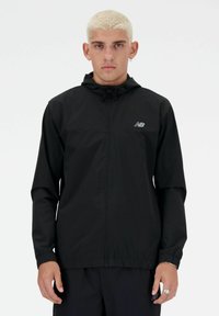 Giacca leggera nera con cappuccio, chiusura con zip e polsini elastici. Presenta un piccolo logo sul petto e una superficie liscia e opaca.