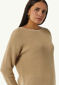 Khakifarbener Strickpullover mit strukturiertem Muster, Rundhalsausschnitt und kontrastierendem weißen Saum. Lässt sich in einer lässigen Passform und mit langen Ärmeln tragen.