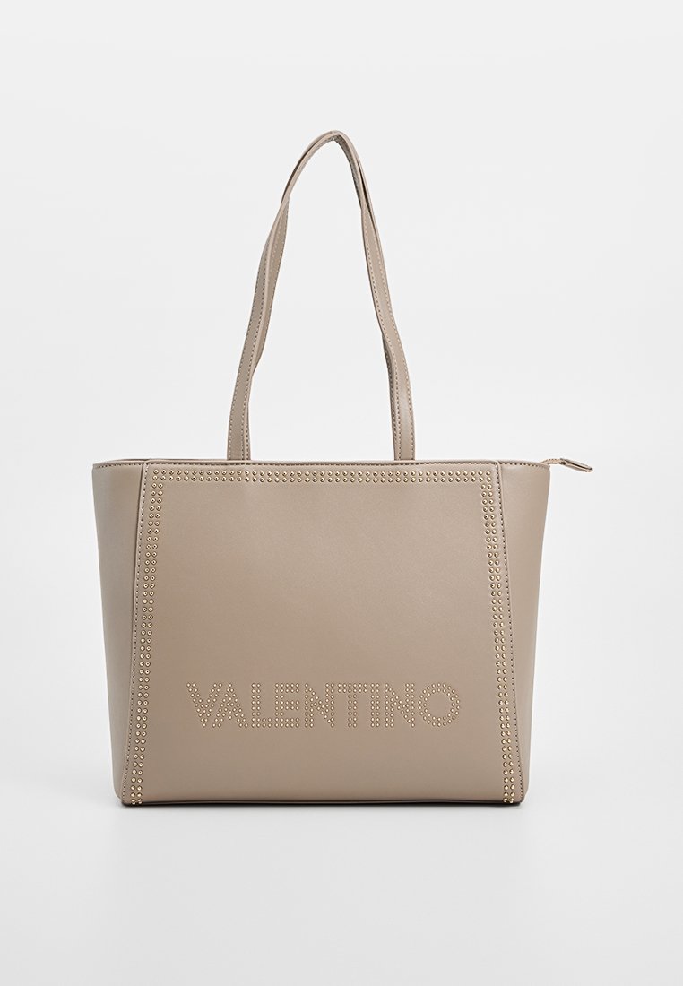 Bolso tote beige hecho de un material suave y resistente con un contorno de tachuelas y "VALENTINO" grabado en la parte frontal. Dos largas correas para el hombro.