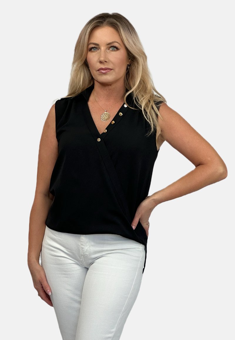 Czarna bezrękawnikowa bluzka z przewiązaniem, z akcentami złotych guzików i głębokim dekoltem w serek, zestawiona z białymi dopasowanymi spodniami.