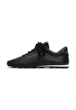 Zapatillas deportivas de cuero negro con acabado suave, punta de forma, suela de goma plana, diseño de cordones y acentos de remaches a lo largo del costado.