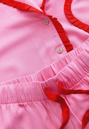 Vaaleanpunainen mekko, jossa on punaiset röyhelökoristeet ja nappikiinnitys, vyötäröllä on kerrostettu muoto ja pehmeä tekstuuri. Liukas kangas, jossa on kontrastivärit.