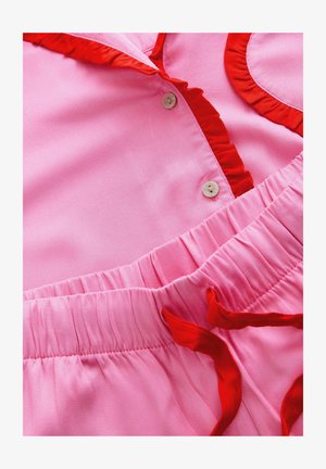 Vestido rosa con acentos rizados rojos y cierre de botones, presentando una cintura fruncida y una textura suave. Tela lisa con detalles en contraste.