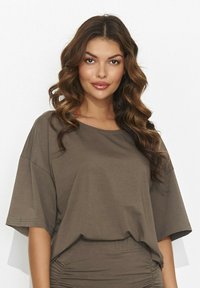 Brązowy,oversize'owy t-shirt z bawełny, z okrągłym dekoltem, krótkimi rękawami i miękką teksturą. Lekko zbierany detal u dołu.