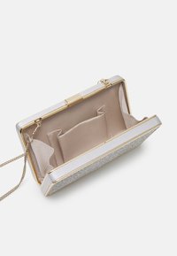 Pieni suorakulmainen clutch, jossa on hopeinen kimalteleva ulkopinta, kullanvärinen kehys, beige kangaspinnoite sisäpuolella, ketjuolkapanta ja useita sisätaskuja.