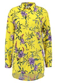 Camicia gialla con colletto, caratterizzata da un motivo floreale in viola e verde, maniche lunghe e una tasca sul petto.