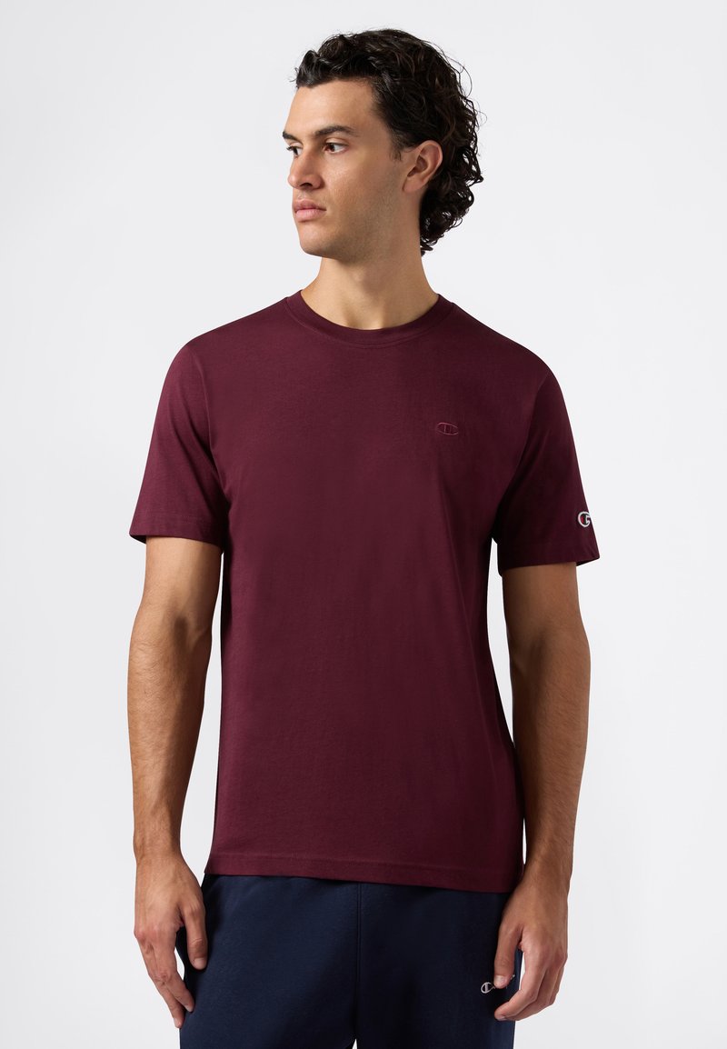 T-shirt bordeaux a maniche corte in cotone con collo rotondo, caratterizzato da un piccolo logo ricamato sul petto e un logo sulla manica.