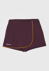 Bordeaux színű sportnadrág, amelynek átlapolt kialakítása van, sárga díszítéssel és hímzett logóval a bal alsó részen. Simább szövettextúra.