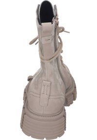 Bottines beige clair avec une finition brillante, devant à lacets, fermeture éclair sur le côté et semelle en caoutchouc épaisse et texturée. Détails de couture subtils.