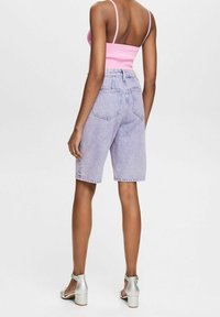 Shorts de mezclilla color púrpura claro con un ajuste holgado y bolsillos traseros, combinados con una camiseta sin mangas ajustada rosa y sandalias plateadas de tacón.