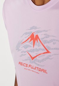 Helllila sportliches Shirt mit rundem Halsausschnitt, das eine Grafik eines Berges in Rot und Blau zeigt, sowie den Text "ASICS FUJITRAIL" darunter.