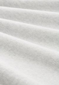 Hellgrauer Stoff mit weicher Textur, der subtile Falten und eine glatte, gleichmäßige Oberfläche aufweist. Eingeschränkte sichtbare Struktur ohne Muster.