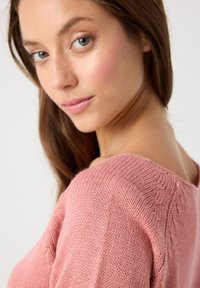 Suéter de punto rosa con un escote amplio, detalles de puntada texturizada y una tela suave y liviana con un corte relajado.