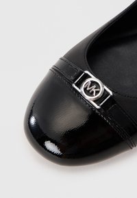 Zwarte ballerina's met een glanzende lakafwerking, voorzien van een metalen logo-buckle en een zachte textuur, ronde neus en een gestikte band.