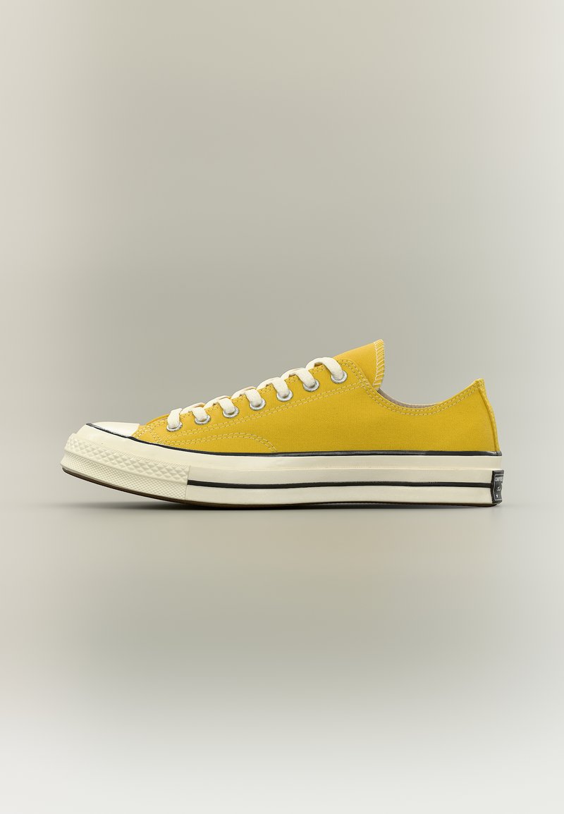 Baskets basses en toile jaune avec des lacets blancs et une semelle en caoutchouc blanche épaisse bordée de noir, vues de profil.