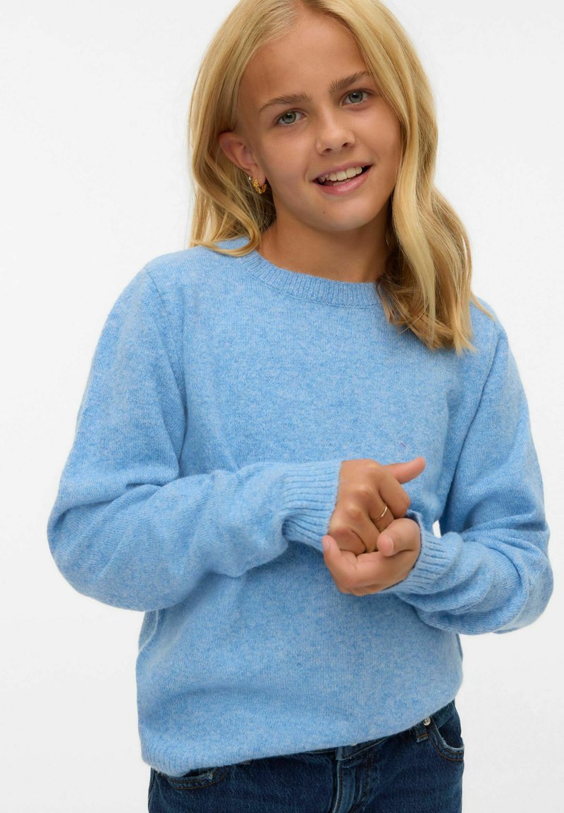 Ljusblå, mjuk stickad tröja med rund hals, ribbade ärmslut och nederkant. Bärs med mörka jeans, vilket visar en avslappnad passform och slät textur.