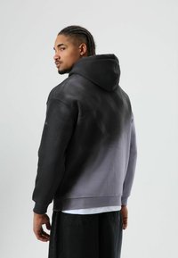 Kaptrui met een verloop van zwart naar grijs. Gemaakt van zachte stof, met een ontspannen pasvorm en geribbelde manchetten.