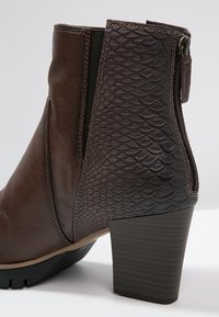 Brown ankle boot with textured snake pattern on the side panel, side zipper closure, and a stacked heel. Smooth leather upper finish.