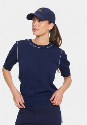 Navy korte mouw trui met een ronde halslijn, voorzien van witte accentstiksels langs de schouders en de onderrand. Zachte gebreide textuur.
