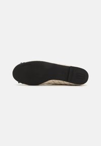 Ballerinas mit einem gesteppten beigen Obermaterial und einer schwarzen Gummisohle. Sie verfügen über eine abgerundete Zehenpartie und ein minimalistisches Design. Markenlogo auf der Sohle.