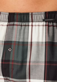 Boxers en coton à carreaux, présentant un mélange de couleurs blanches, grises, vertes et rouges. Taille élastique avec un accent de bouton et une étiquette de marque.