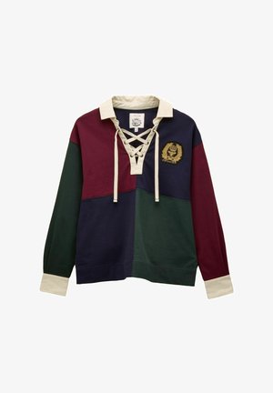 Dlhý rukáv ragbyové tričko s krémovým golierom, šnúrkovým výstrihom, emblémom na hrudi a farebnými blokmi v burgundskej, námorníckej a tmavozelenej farbe.