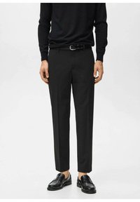 Czarne, dopasowane spodnie o prostym kroju, wykonane z gładkiej tkaniny, zestawione z czarnym paskiem i wypolerowanymi czarnymi mokasynami.