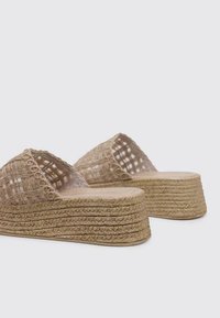 Sandalias de plataforma beige tejidas con un upper texturizado, diseño de punta abierta y suela de yute apilada para mayor altura y agarre.