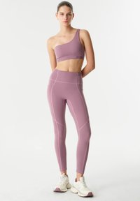 Paarse sportbeha met één schouder, gecombineerd met hooggeoriënteerde legging, met contrasterende stiksels en een soepele, rekbare textuur.