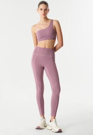 Paarse sportbeha met één schouder, gecombineerd met hooggeoriënteerde legging, met contrasterende stiksels en een soepele, rekbare textuur.