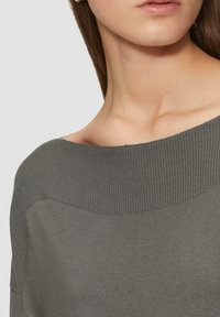 Grijze trui met een brede, geribbelde halslijn en een gladde textuur, met een aansluitend model en subtiele naaddetails.