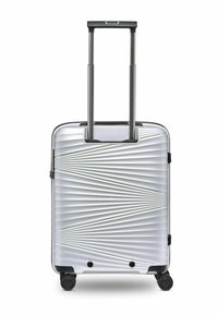 Silberner Hartschalenkoffer mit geometrischem Rillenmuster, ausziehbarem Griff, vier Rädern und schwarzen Akzenten an der Basis und den Ecken.
