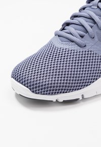 Lyse lilla atletiksneaker med mesh-overdel, tekstureret overflade, forstærket tåhætte og hvid gummisål.