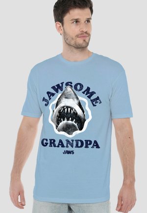 Man wearing light blue T-shirt with a large shark head graphic and text "Jawsome Grandpa Jaws" on the front.