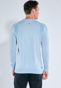 Hellblaues Sweatshirt mit gerippten Schulterdetails und lässiger Passform. Verfügt über ein Etikett am Nacken und eine feste, glatte Textur.