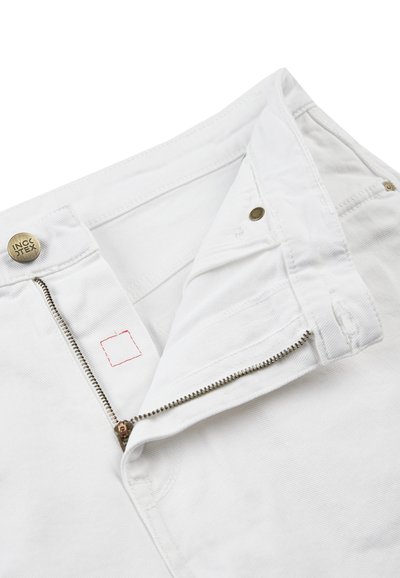 Jeans de mezclilla blanca con cierre de cremallera y botón de latón. Cuenta con un bolsillo oculto con detalle de costura roja. Textura suave.