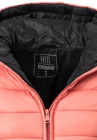 Veste matelassée rose avec doublure intérieure noire et fermeture éclair frontale, avec une étiquette de taille petite indiquant "BASIC BYMARIKOO OUTERWEAR."