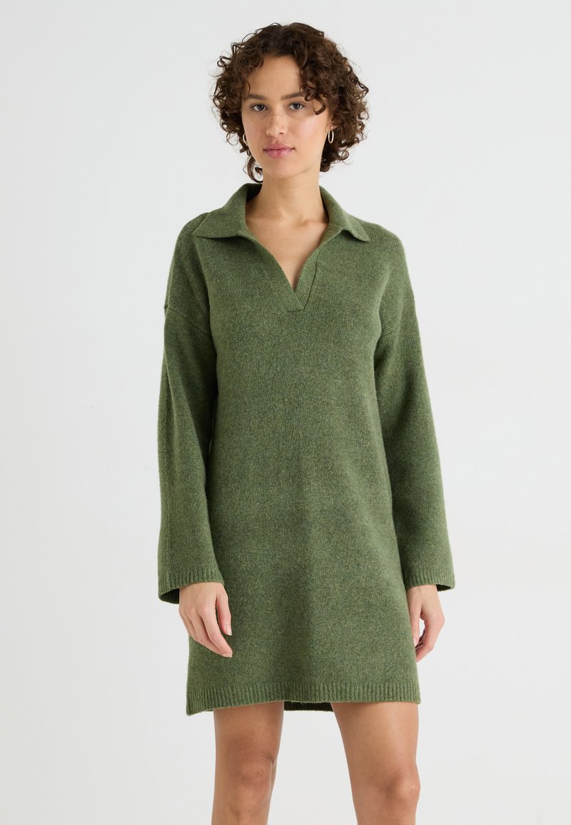 Strikket grønn kjole med krage, lange ermer og en avslappet passform. Stoffet har en myk tekstur og subtile variasjoner i nyanse.