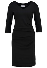 Robe noire ajustée jusqu'aux genoux avec manches trois-quarts et encolure en V arrondie, en tissu lisse.