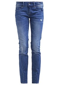 Jeans skinny de mezclilla azul oscuro con un ligero desgastado, parches desgastados, cinco bolsillos y cierre de botón metálico en la cintura.