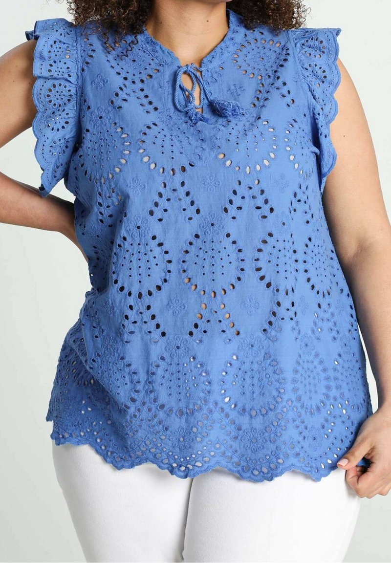 Blusa blu ricamata con maniche e orlo a scallop, caratterizzata da motivi a intaglio e un nodo al collo. Tessuto di cotone testurizzato.