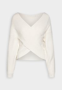 Vit kortad tröja med en texturerad stickning, som har en V-ringning och ett överlappande framdesign. Långa ärmar med åtsittande manschetter.